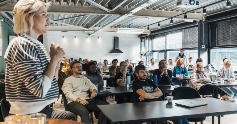 Best Workplaces 2026 : une formatrice anime un atelier de management devant une trentaine de salariés dans un loft industriel