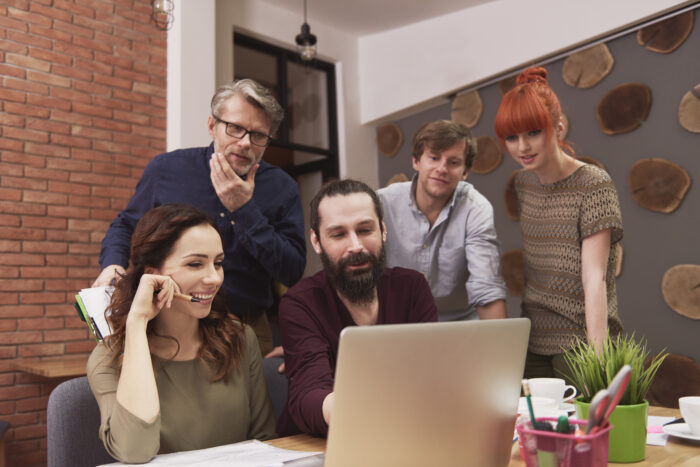 Un groupe de collaborateurs d'âges différents échangeant autour d'une interface d'IA, illustrant la synergie intergénérationnelle en entreprise.