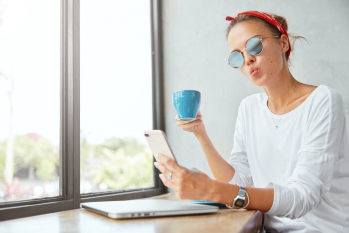 Une jeune collaboratrice souriante organisant son emploi du temps sur tablette depuis un café, illustrant la liberté et la flexibilité au travail attendues par la Génération Z.