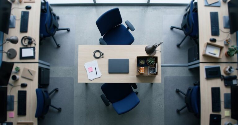 Poste de travail vidé vu du dessus dans un open space, chaise repoussée et carton d'affaires personnelles, illustration du coût du turnover