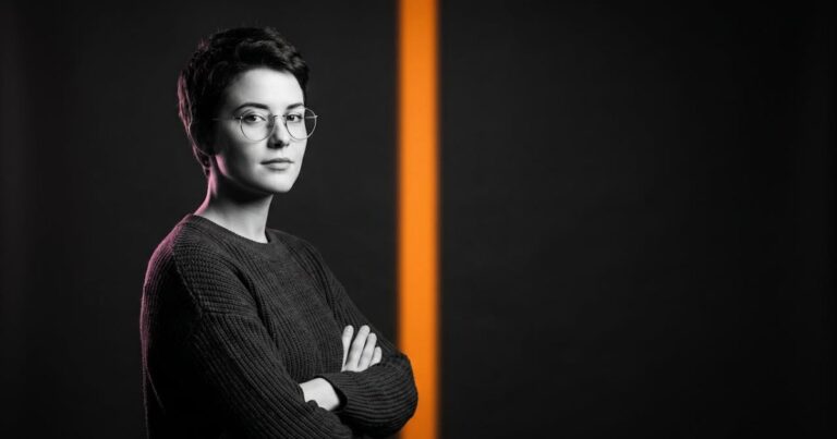 Portrait en noir et blanc d'une jeune ingénieure en machine learning, bras croisés, avec une bande de lumière orange, illustration des compétences IA rares en recrutement