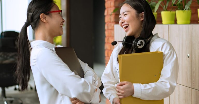 Deux collegues souriantes echangeant au bureau, engagement collaborateur et marque employeur en 2026