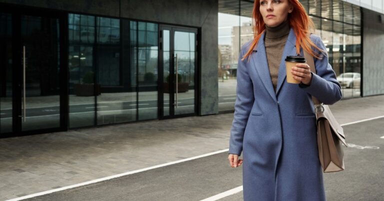 Baromètre Apec-ANDRH 2026 : une cadre en manteau bleu marche devant un immeuble de bureaux, illustration de la relation des cadres à leur fonction RH