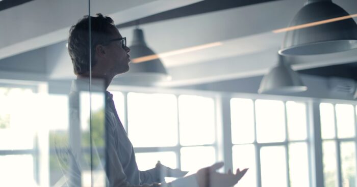 Manager derrière une cloison vitrée dans un bureau contemporain, crise du management intermédiaire et risque de turnover en 2026
