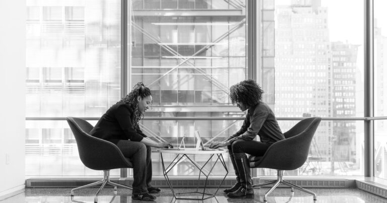 Deux professionnelles en entretien individuel dans un bureau vitré, illustrant l'entretien de parcours professionnel