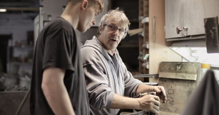 Histoire de la marque employeur : un artisan expérimenté forme un apprenti dans un atelier, héritage du compagnonnage