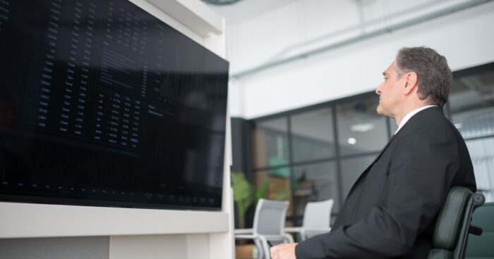 Dirigeant face a un grand ecran de donnees dans un bureau moderne, illustrant la marque employeur analysee par les IA generatives
