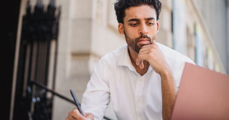 Microshifting : un cadre en chemise blanche travaille sur son ordinateur portable en terrasse, journée de travail fractionnée
