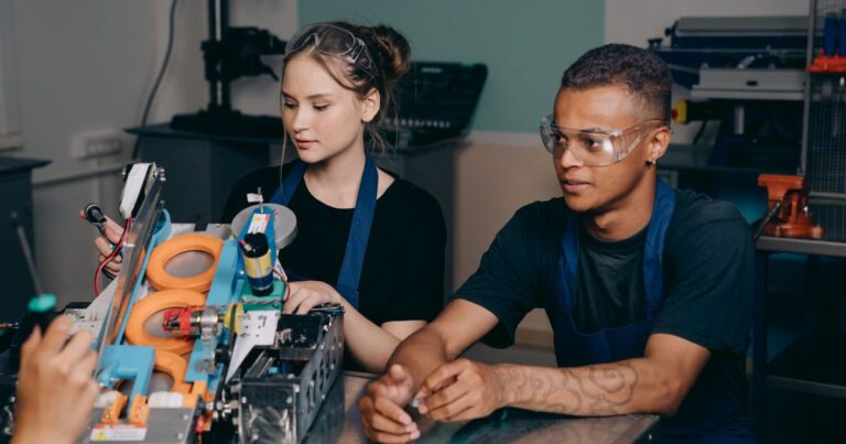 Pénurie de compétences 2026 : deux jeunes techniciens en lunettes de protection travaillent ensemble sur une machine dans un atelier technique