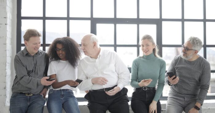 Programme ambassadeurs : une équipe de salariés de tous âges partage du contenu sur smartphone
