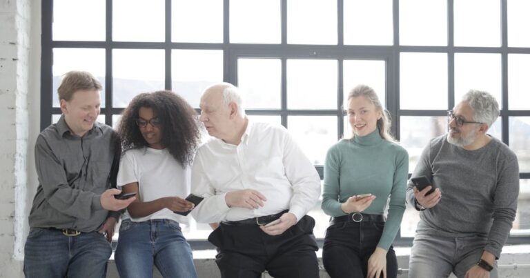Programme ambassadeurs : une équipe de salariés de tous âges partage du contenu sur smartphone