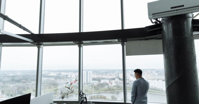 Cadre dirigeant debout dans un bureau en hauteur face à la vue sur la ville, illustrant le marché du recrutement de cadres 2026