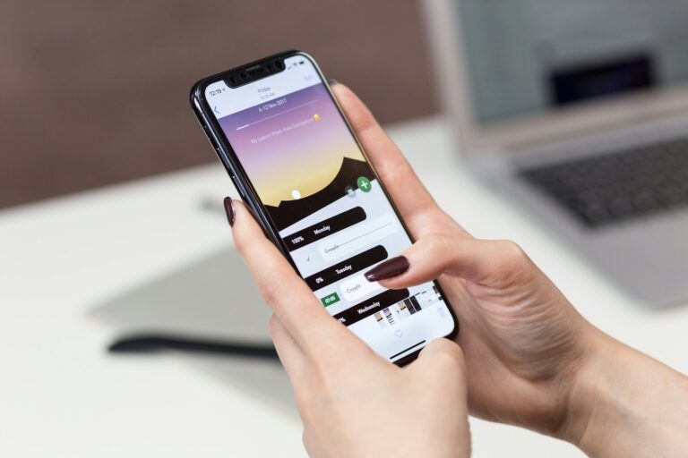 Smartphone tenu en main près d'un ordinateur